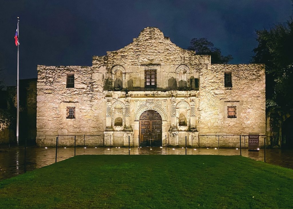 The front of the Alamo illuminated at night.