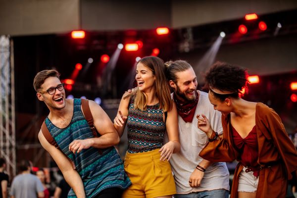 Four young adults laughing together at a concert.