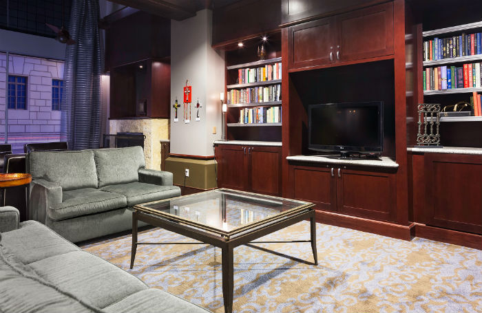 Lounge area with couches, TV, and bookshelves at the Emily Morgan Hotel.
