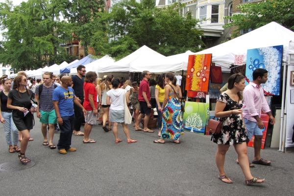 People walking from tent to tent at an outdoor art fair.