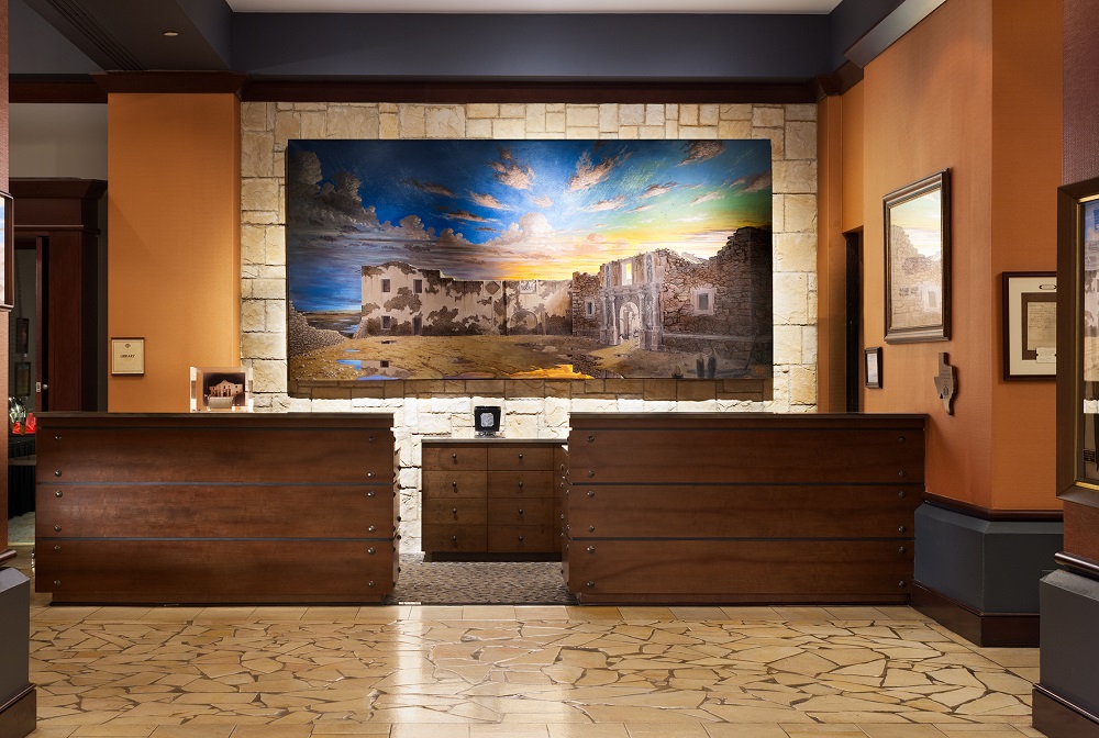 The front desk of the Emily Morgan Hotel, featuring a large painting of the Alamo.