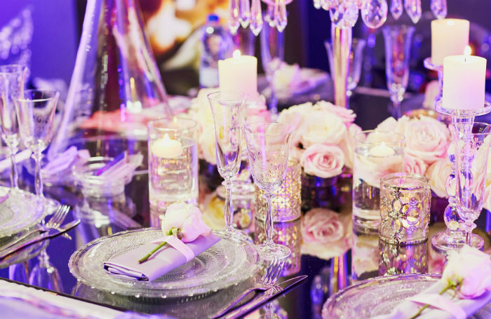 Pink and purple place settings with flowers at a rehearsal dinner.