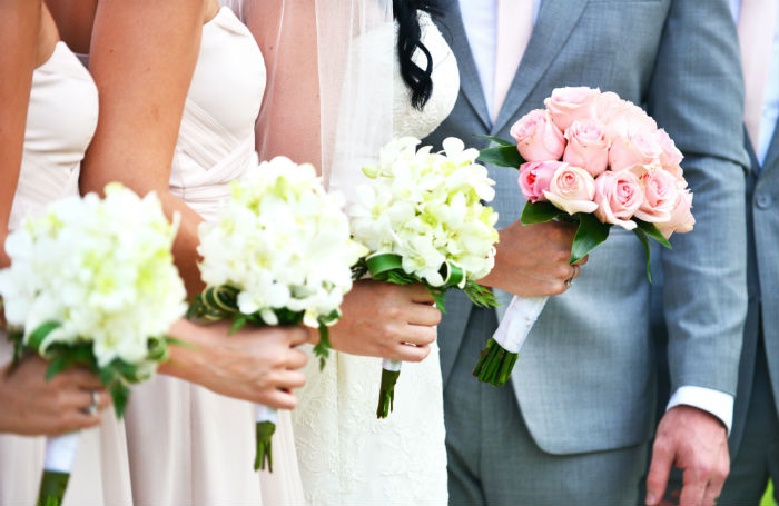 A closeup of the bouquets held by hree bridesmaids and the maid of honor standing at the alter.