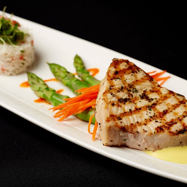 Grilled swordfish with asparagus, rice, and carrot strips.