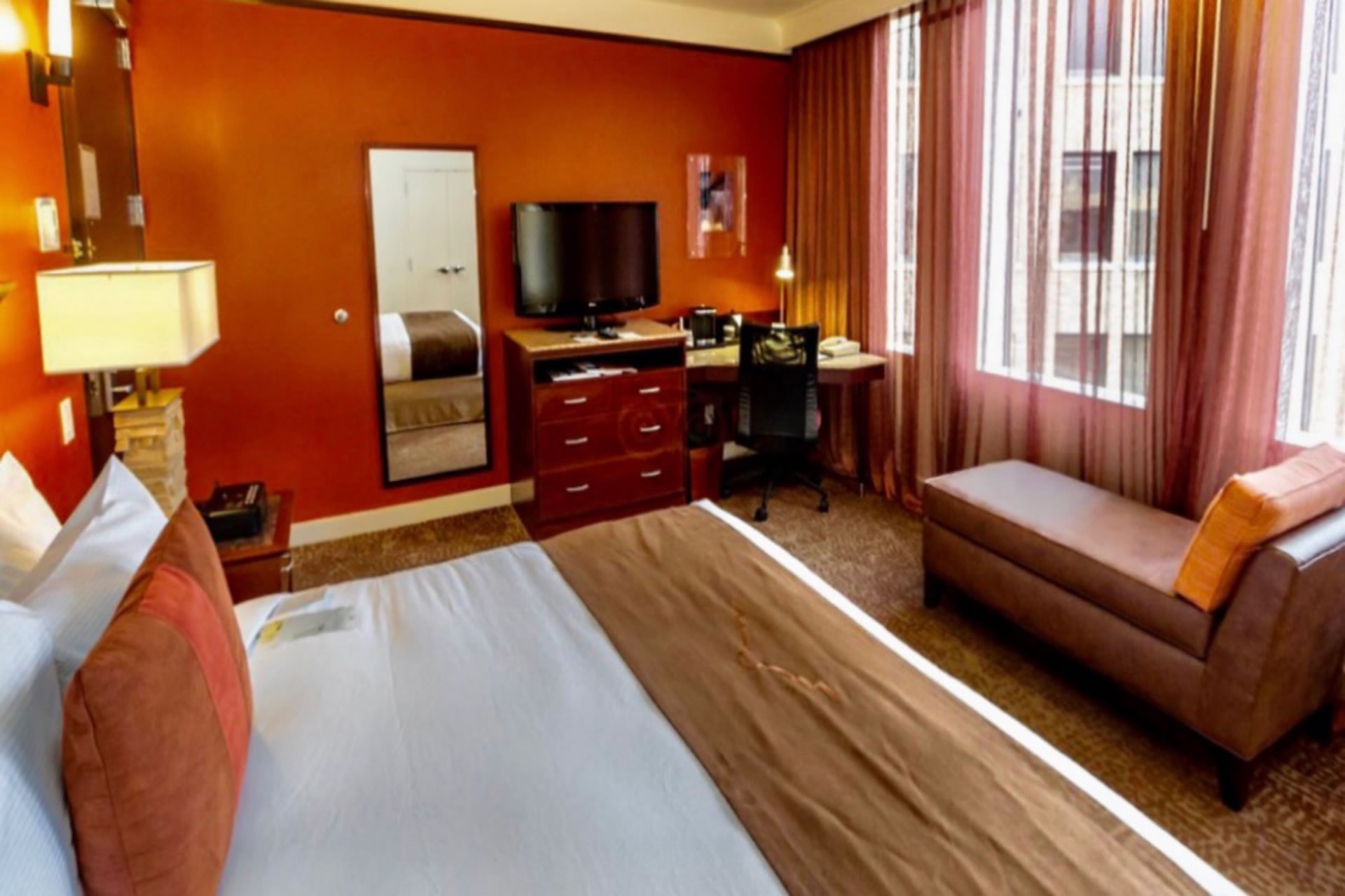 Guestroom at the Emily Morgan Hotel featuring a king bed, work desk, and chaise lounge chair.