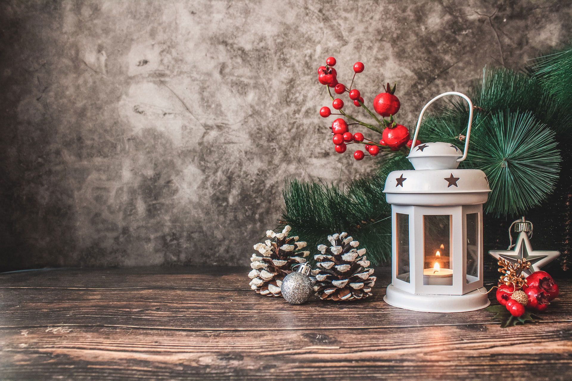 Christmas lantern, pine cones, and ornaments on a wooden table.