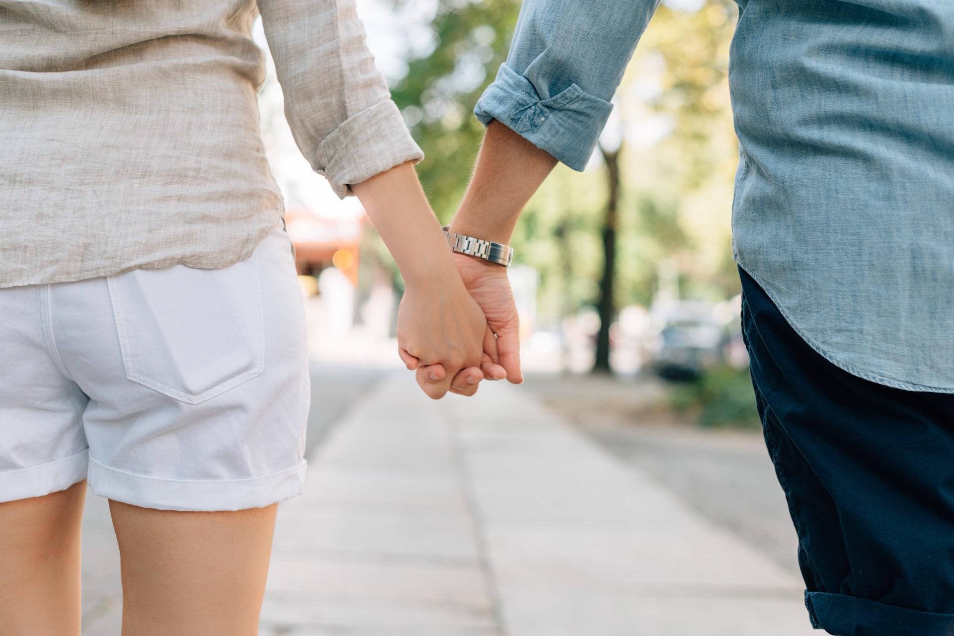 Man and woman holding hands while walking down the street.