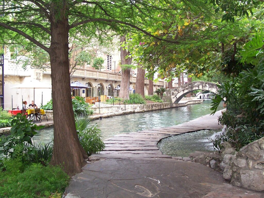 A tree-lined pathway leading to the San Antonio River Walk.