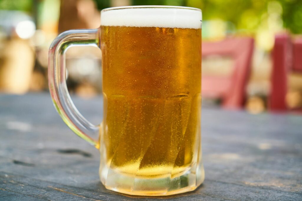 Glass mug of beer on an outdoor table.