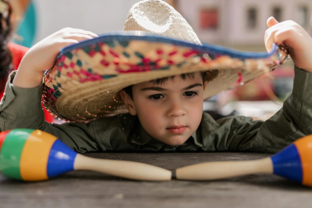Kid in a sombrero looking at maracas.