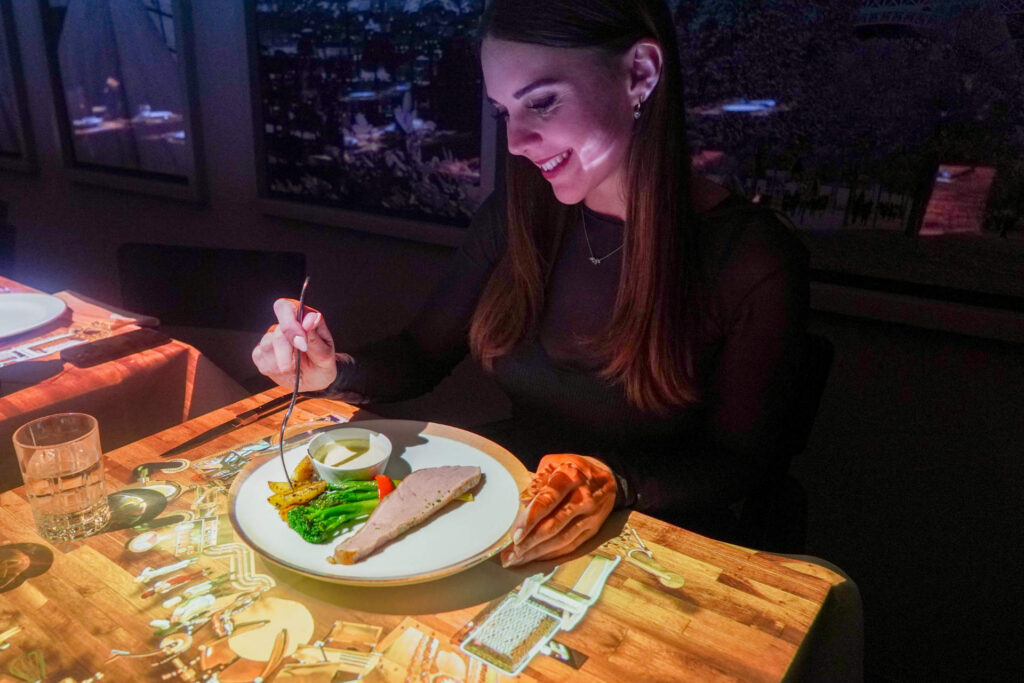 Woman eating an entree at a Le Petit Chef event.