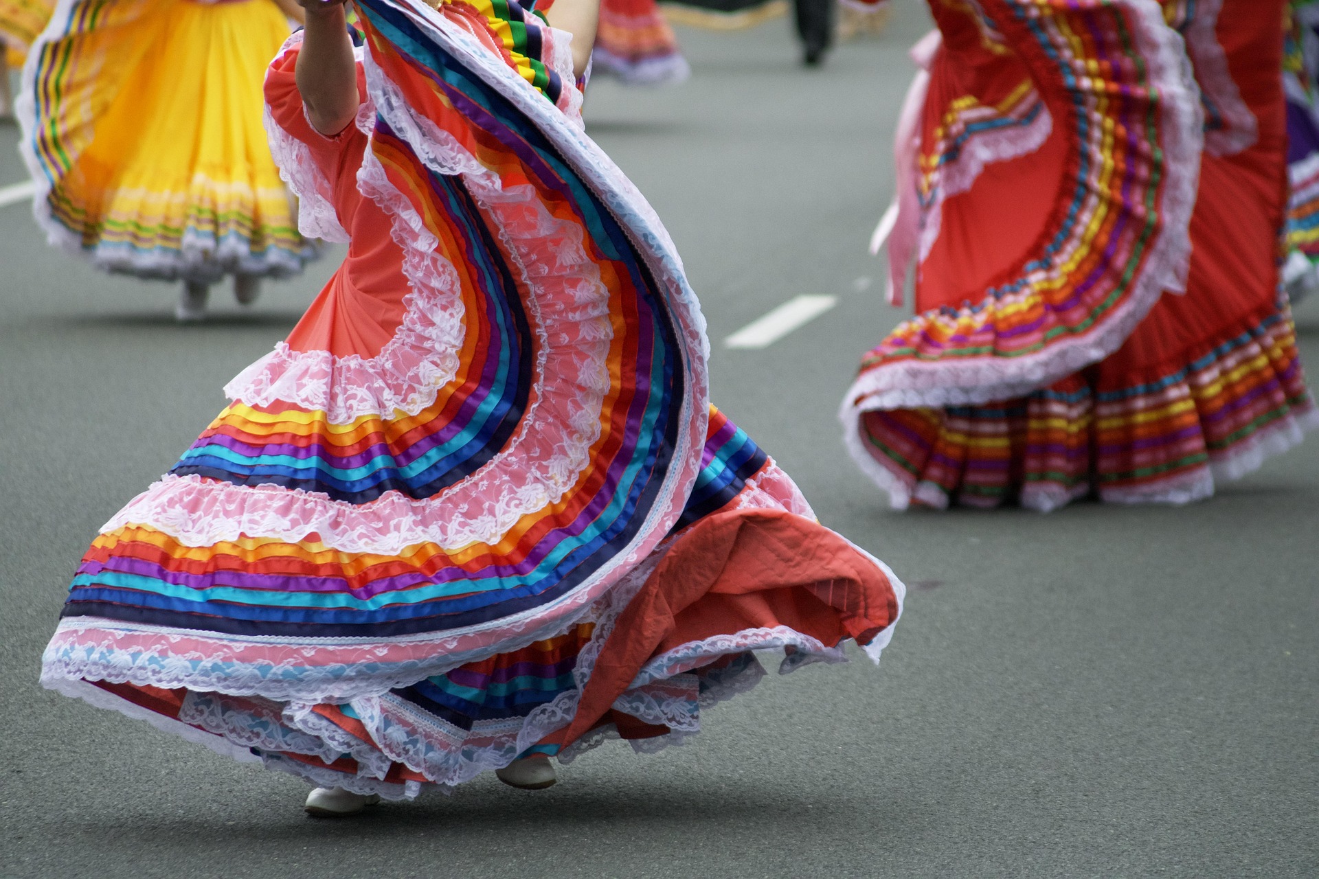 Women dancing in the street in colorful dresses.
